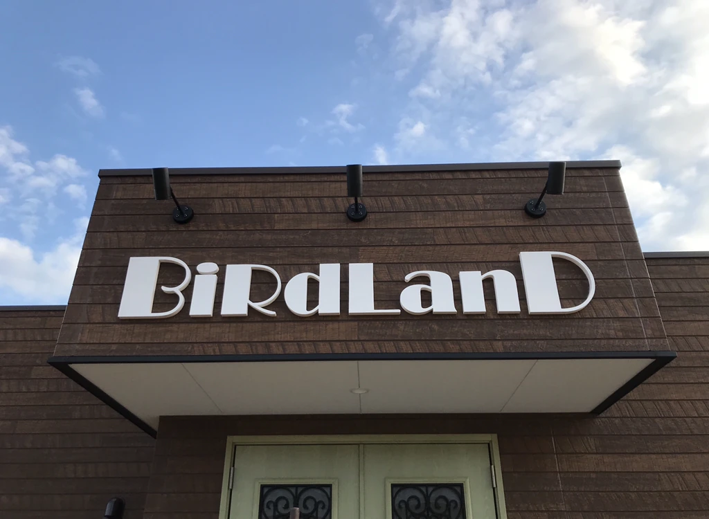 木目の外壁に設置された白いBirdLandの立体文字