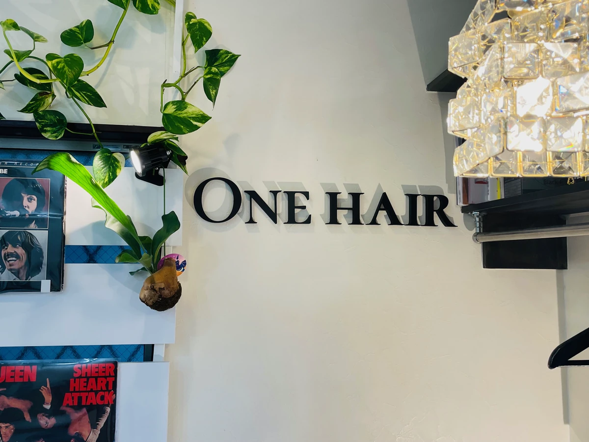 店内の白い壁に設置された黒いONE HAIRのカルプ文字