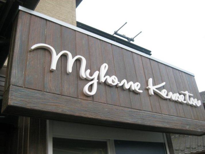 木製の外壁に設置された白い立体切り文字の店舗看板